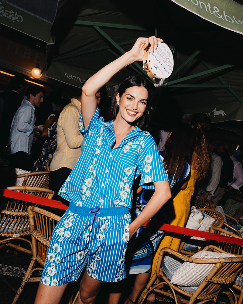 Frau im blauen Sommeroutfit tanzt mit Tamburin in Capri.