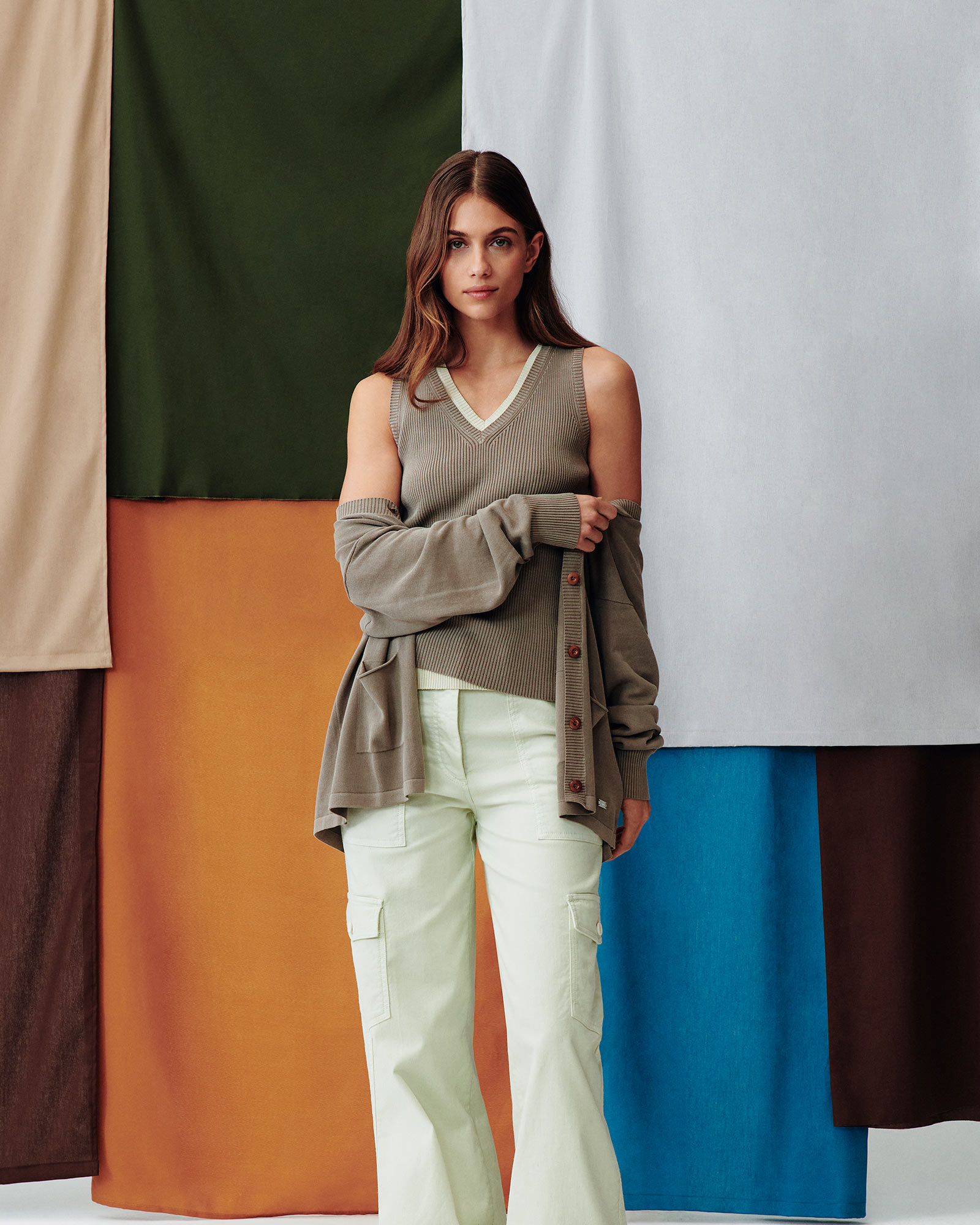 Male model wearing a yellow shirt and peach trousers against a colorful background.