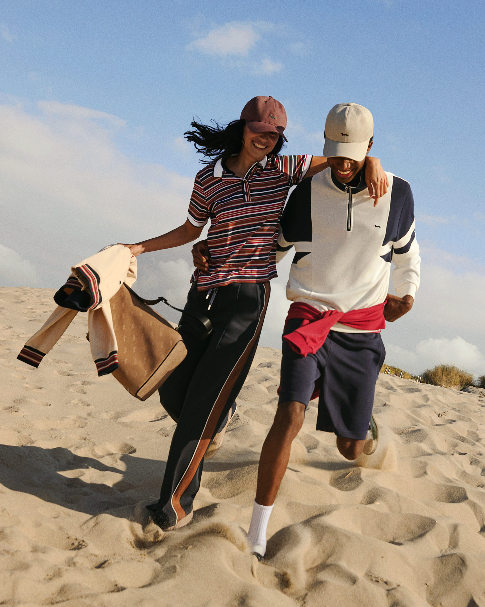 Paar am Strand mit gestreiften Poloshirts und Baseball-Kappen