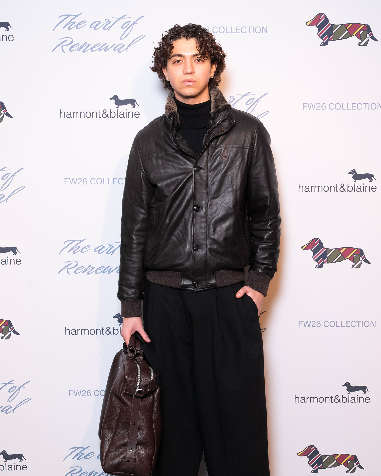 Homme portant blouson en cuir noir et pantalon large sombre avec sac