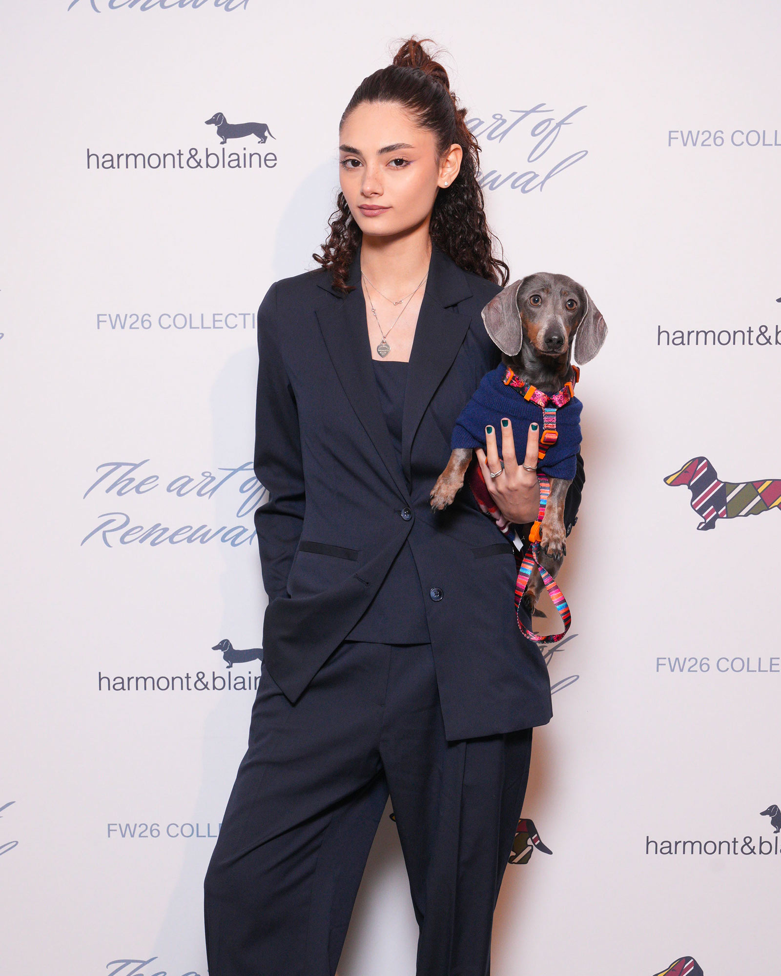 Femme en tailleur sombre tenant un teckel en pull color&eacute;