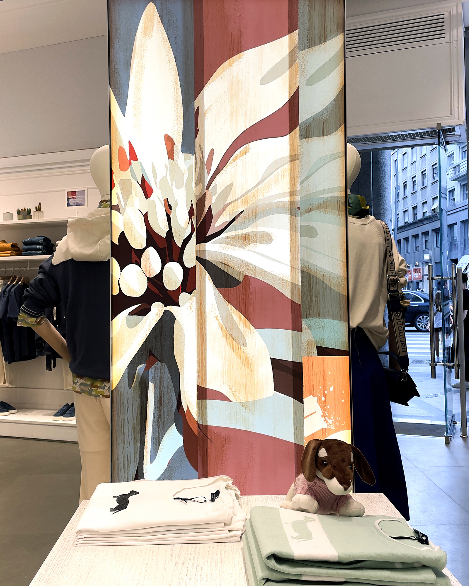 Harmont & Blaine FW25 Schaufenster mit gro&szlig;er stilisierter Blume und Denim- sowie Casual-Outfits.