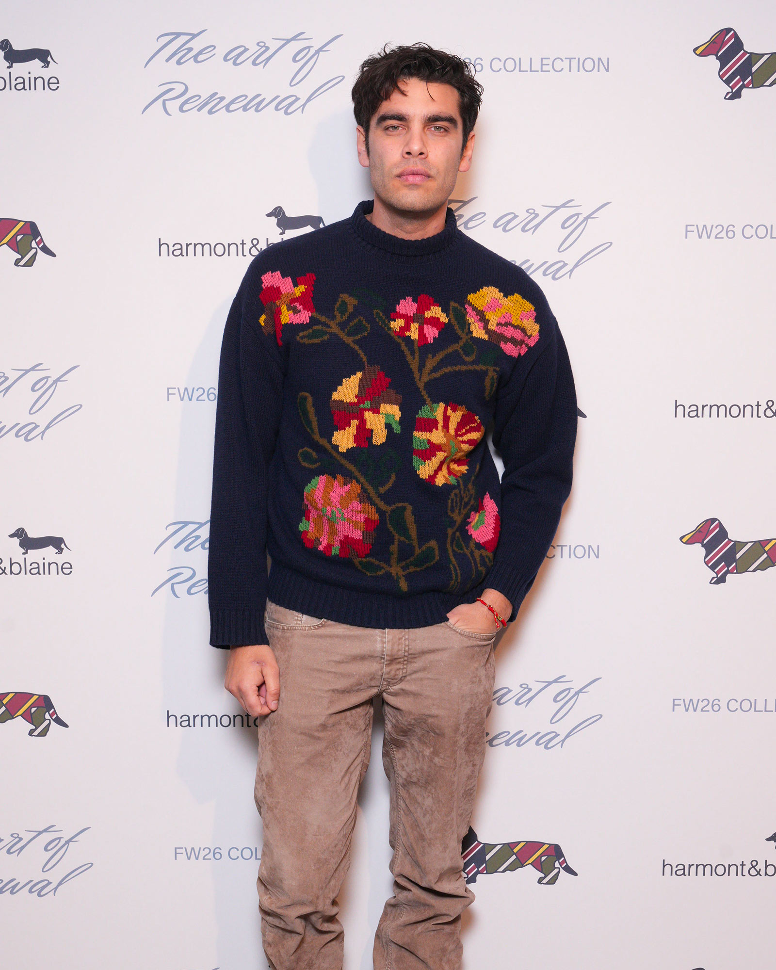 Homme portant pull marine &agrave; broderies florales et pantalon beige