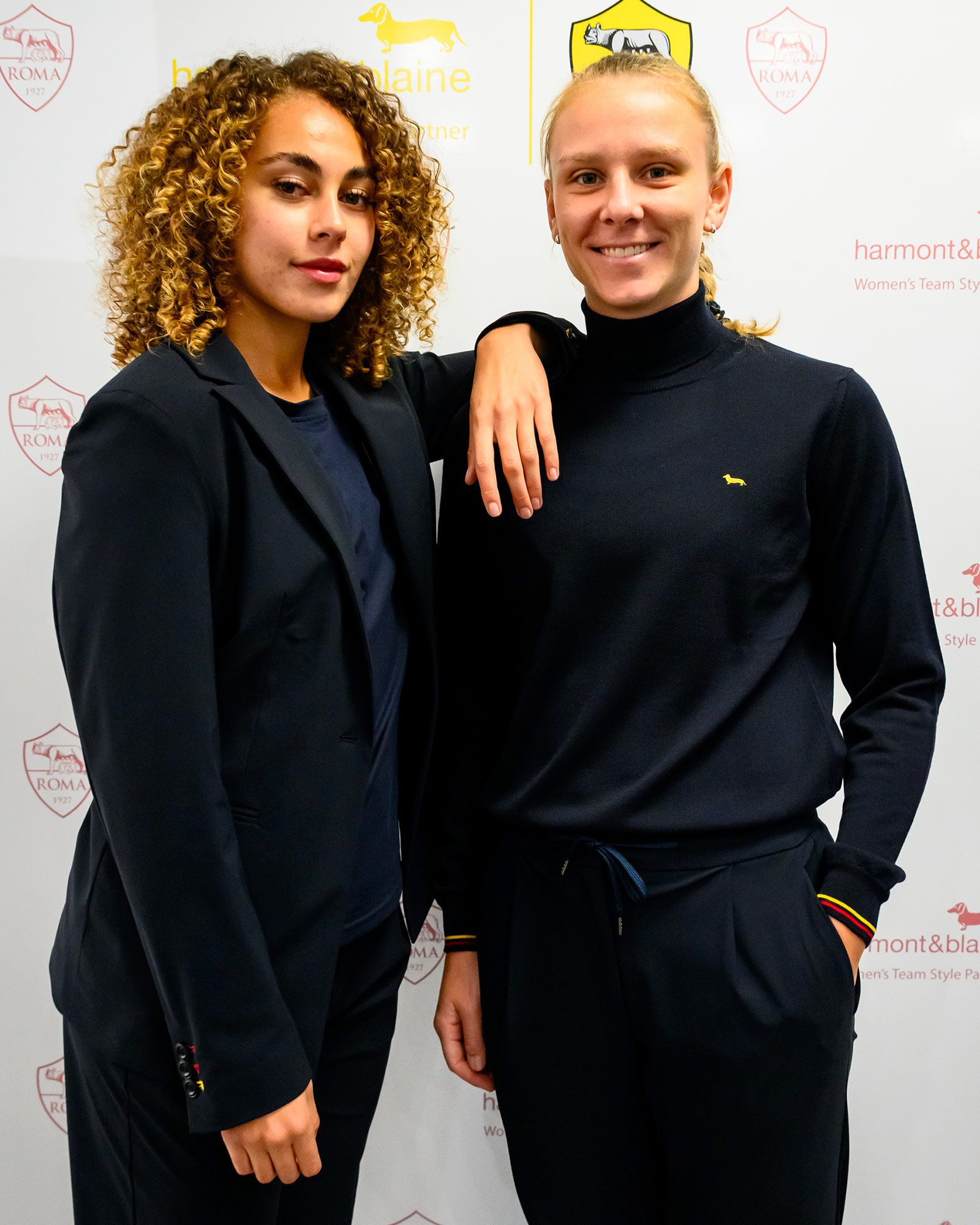 Due donne in uniforme blu navy, una con dolcevita e l&rsquo;altra con blazer.