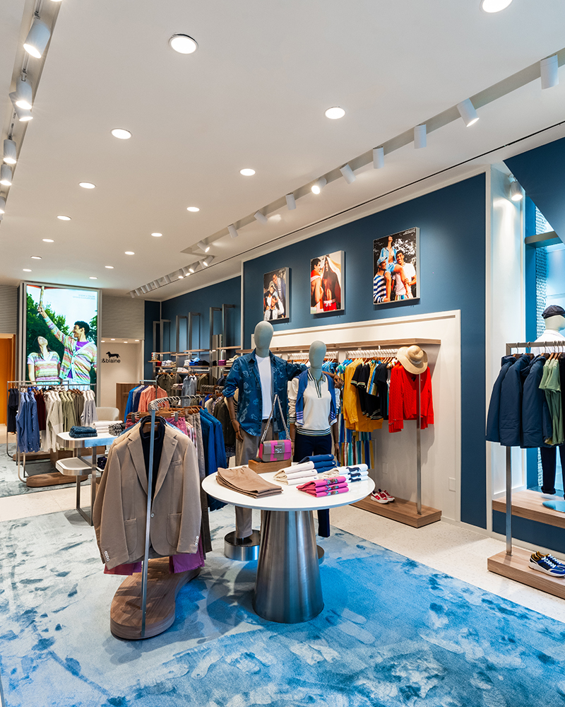 Int&eacute;rieur de la boutique Harmont & Blaine avec v&ecirc;tements color&eacute;s.